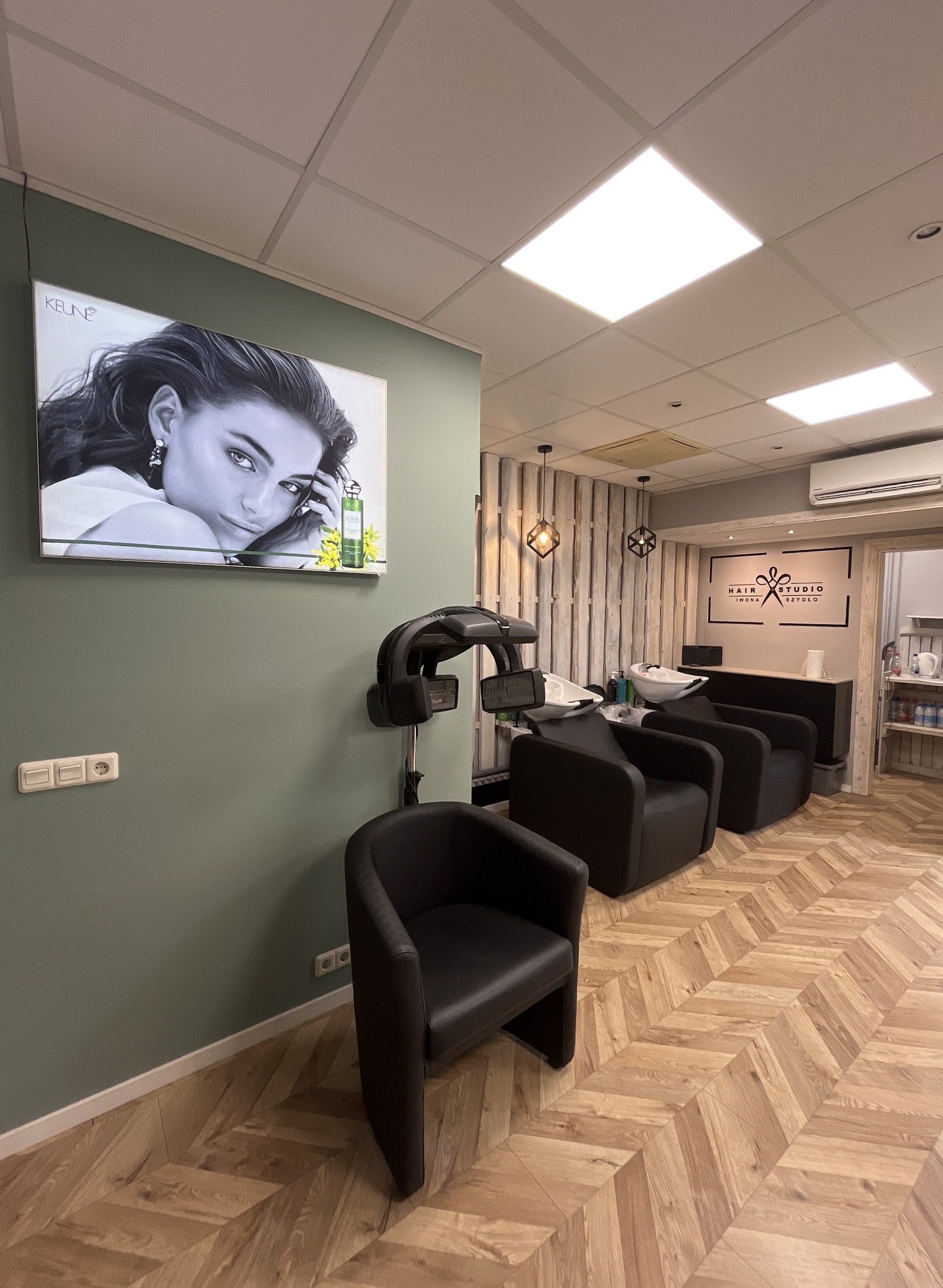 Zicht door de salon naar de wasplekken, met een groot zwart-witportret aan de groene wand